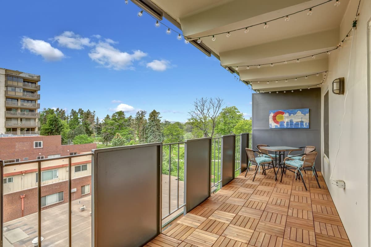 Private balcony with cafe table, Colorado flag wall art and a sweeping view over Cheesman Park