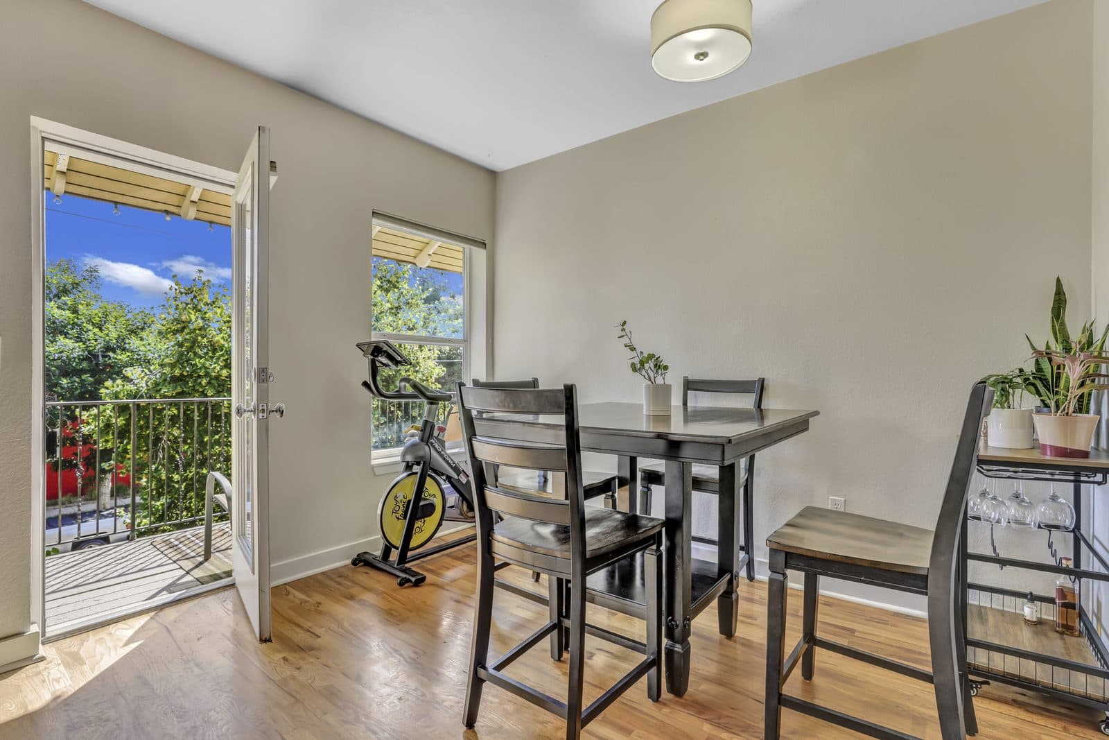Dining nook with high-top table, Peloton bike and balcony door